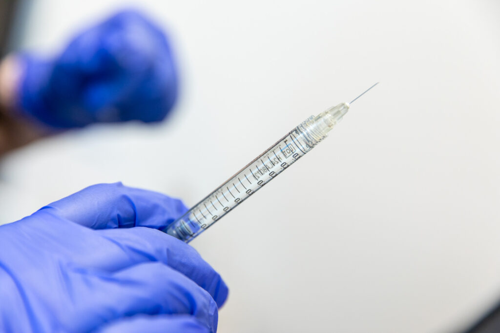 Gloved hand holding syringe.