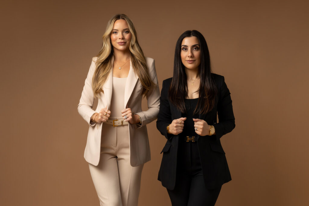 Two women standing next to each other smiling at the camera.