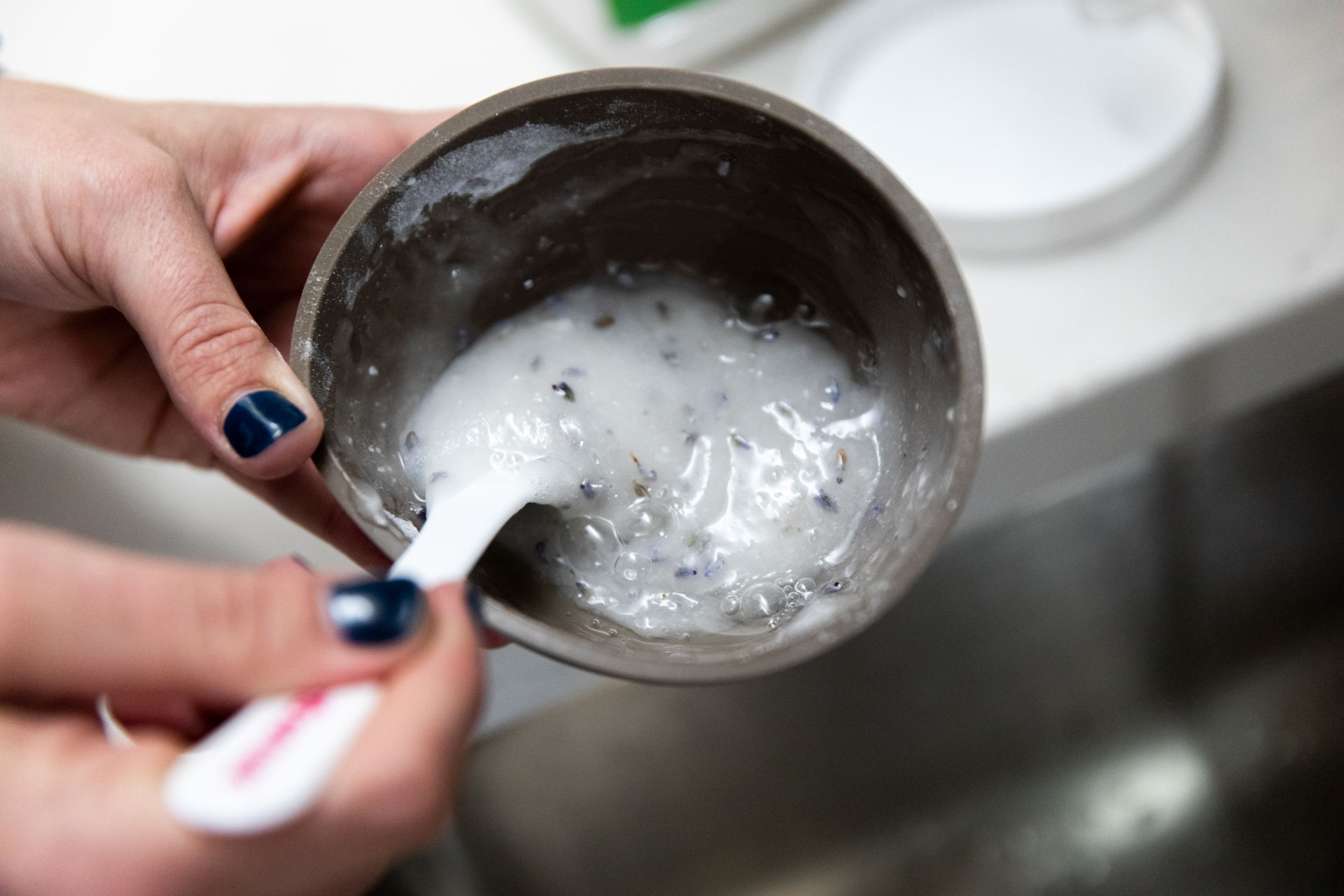 Hands holding facial serum in bowl.