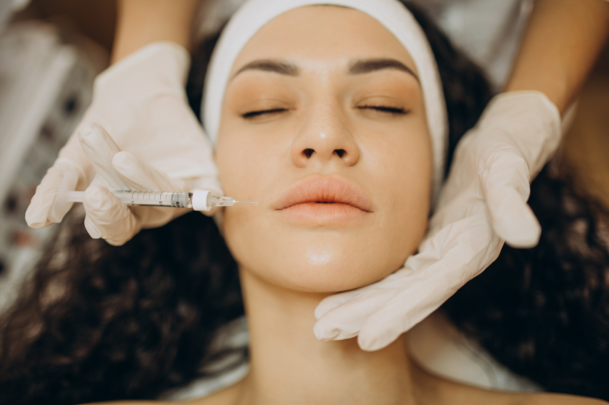 Overhead shot of woman getting needle placed near her lips.