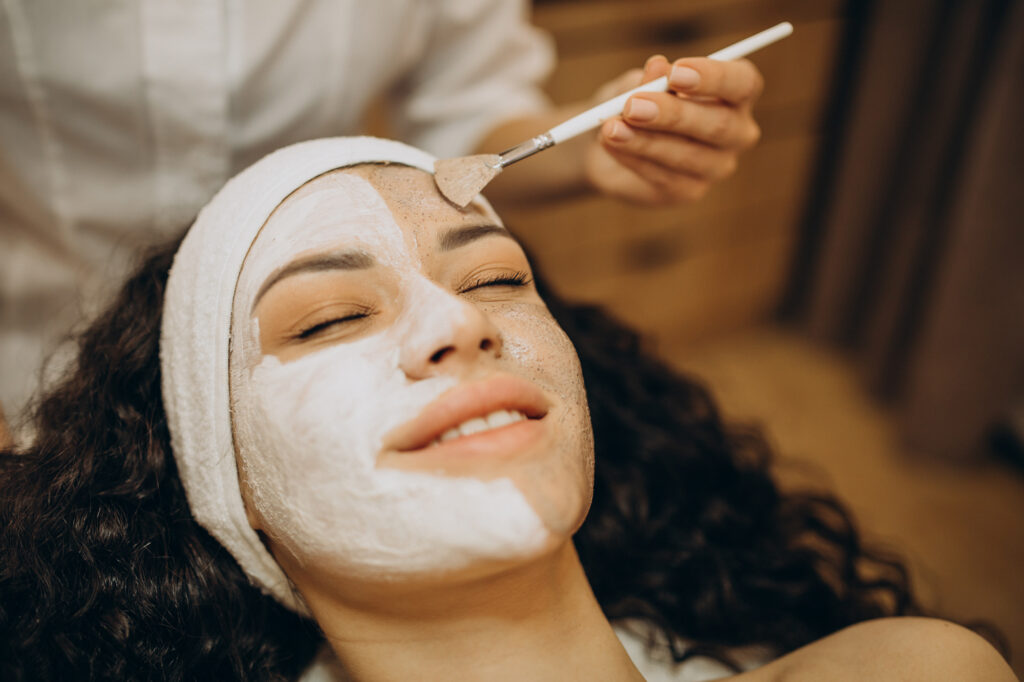 A patient lies down as a provider applies a chemical peel in Denville to her skin.