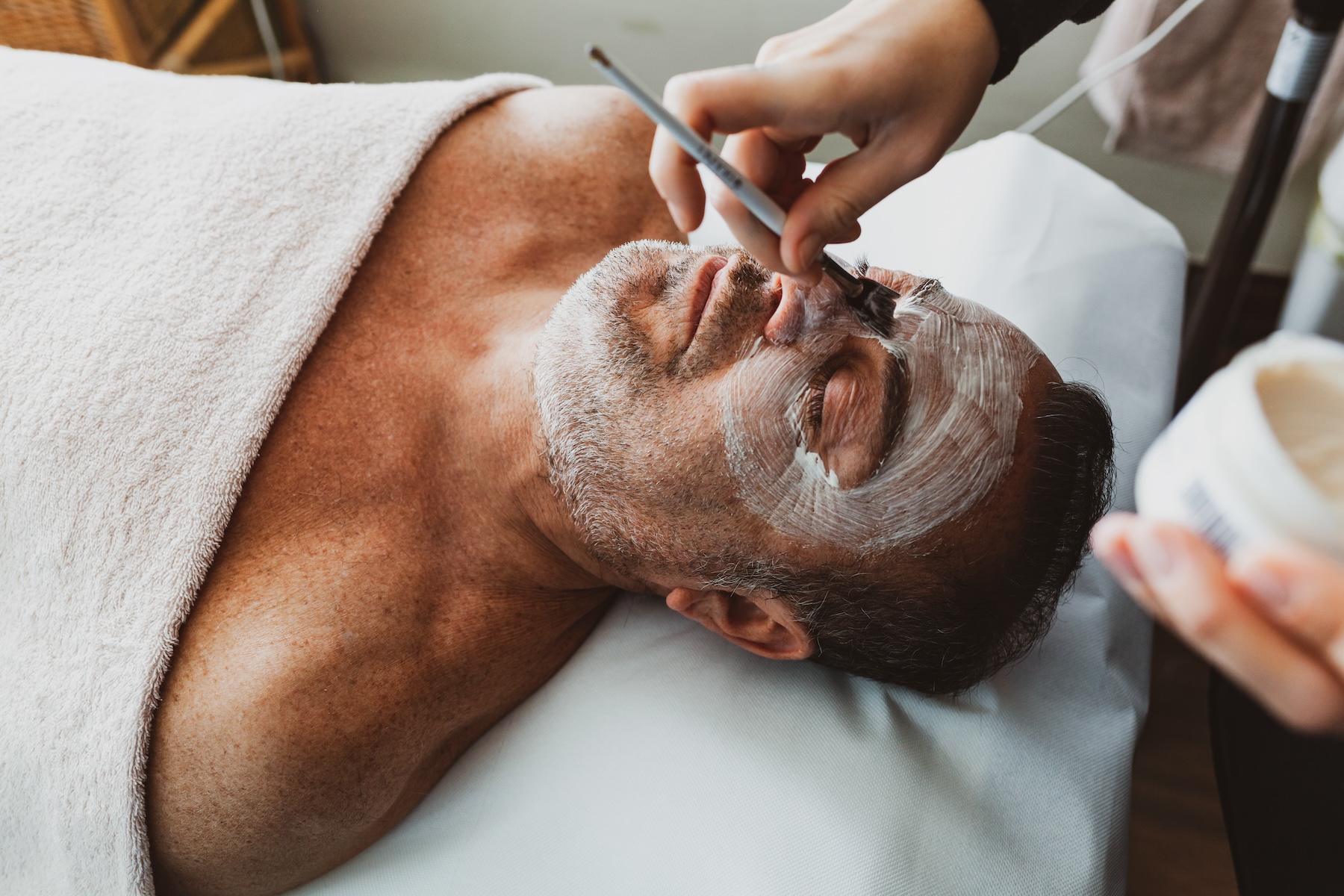 Side angle of middle-aged man receiving face mask with brush.