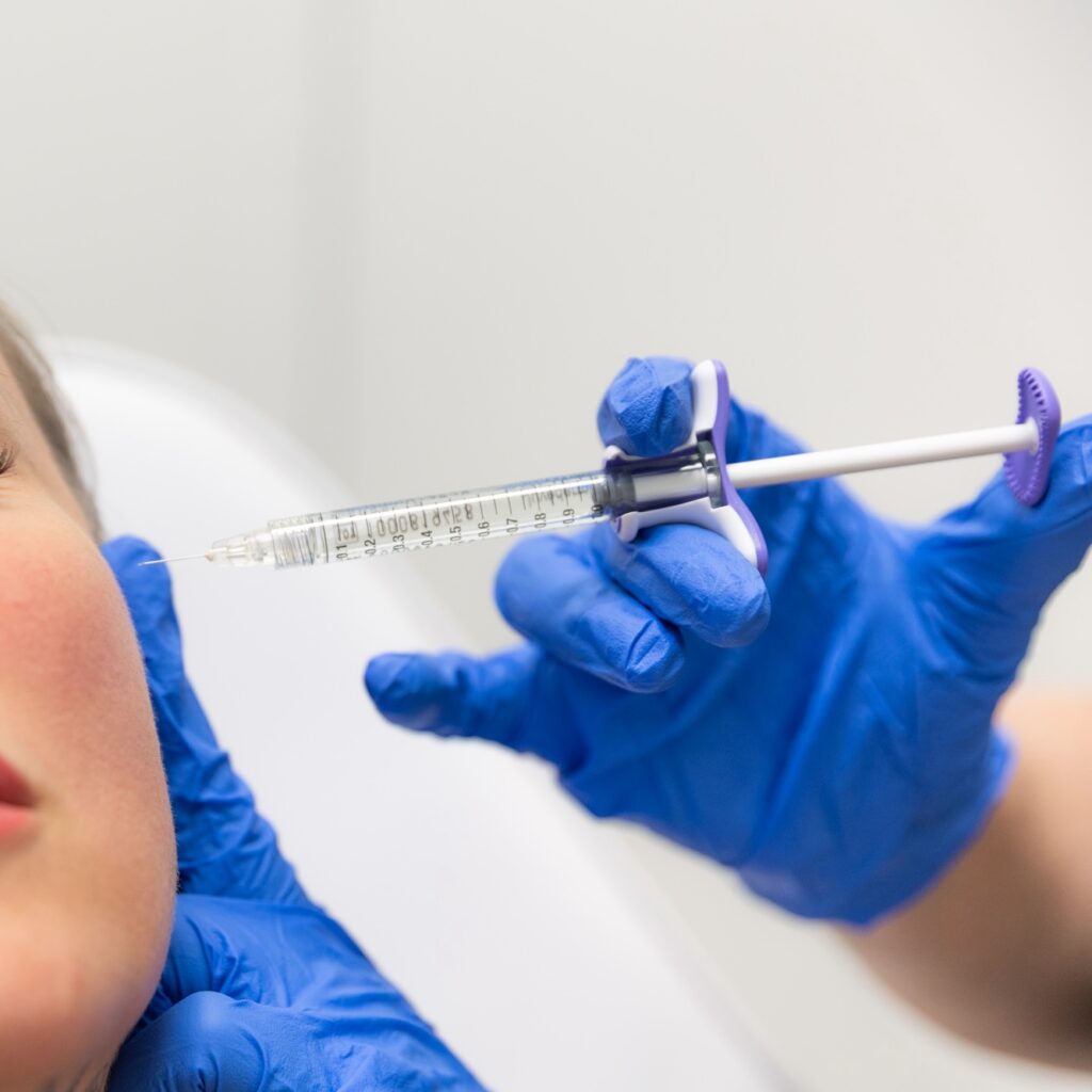 Nurse inserting needle into patient's cheek.