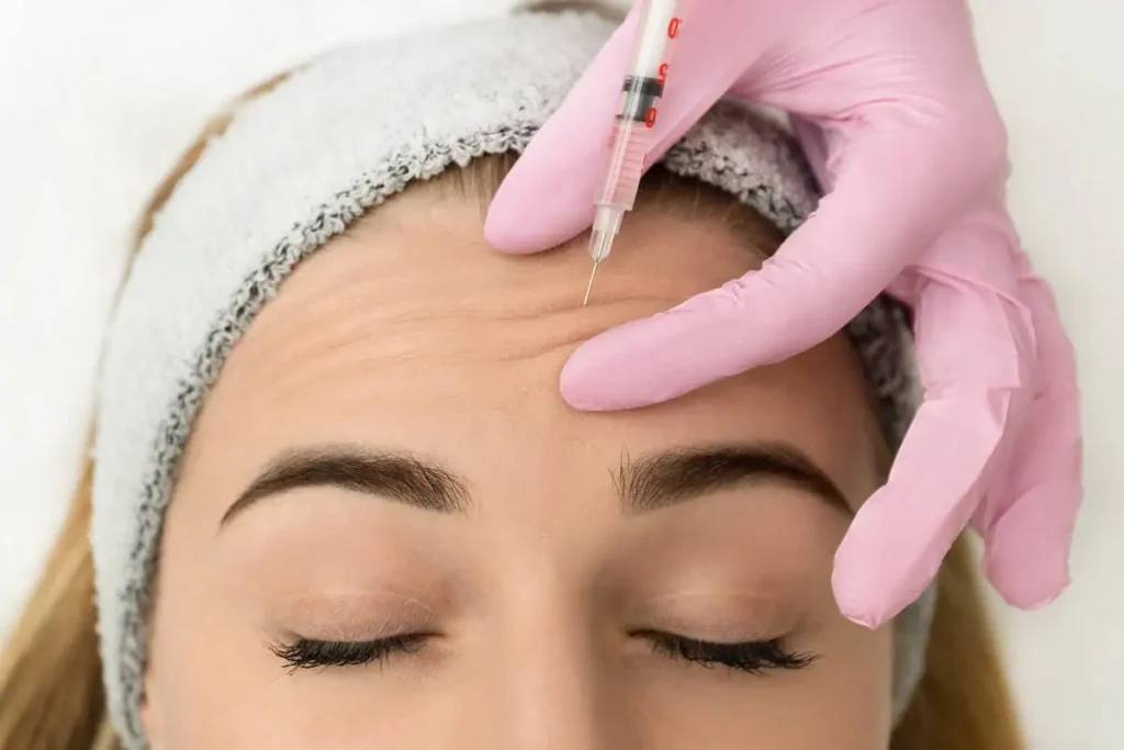 Up-close angle nurse injecting treatment into patient's forehead