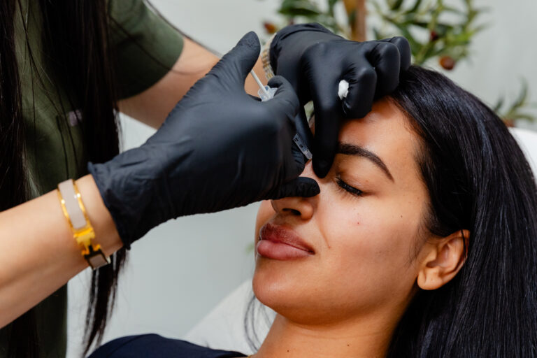 Side angle of nurse injecting Botox on patient's nose