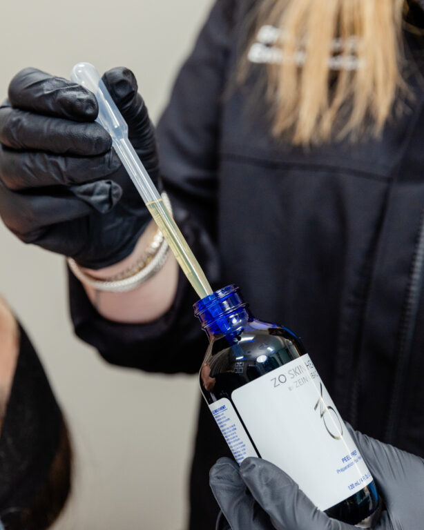 Nurse wearing gloves holding chemical peel bottle and syringe