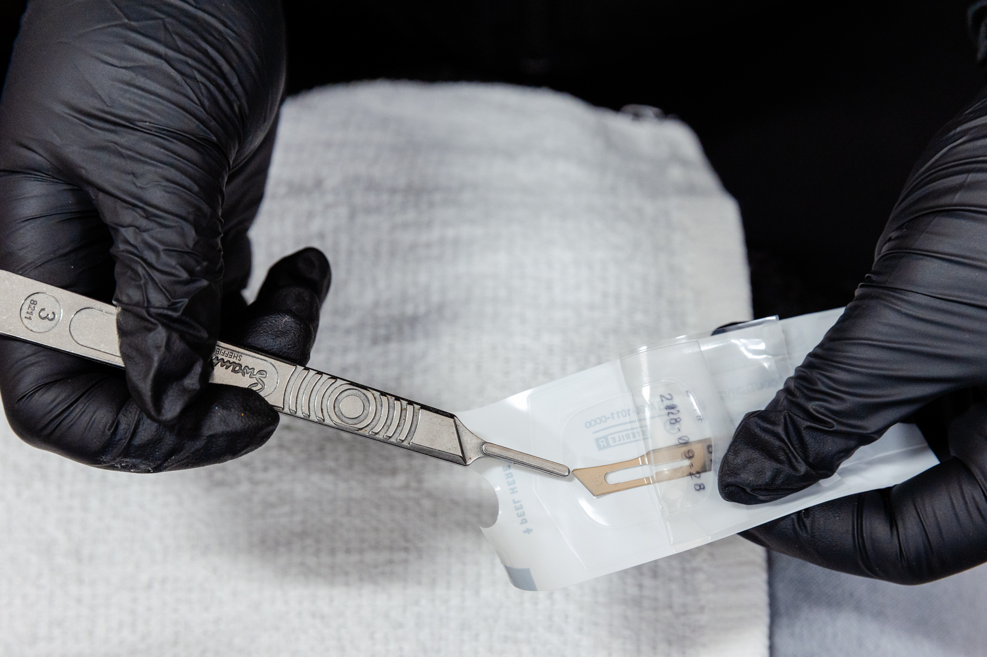 Gloved hands holding dermaplaner