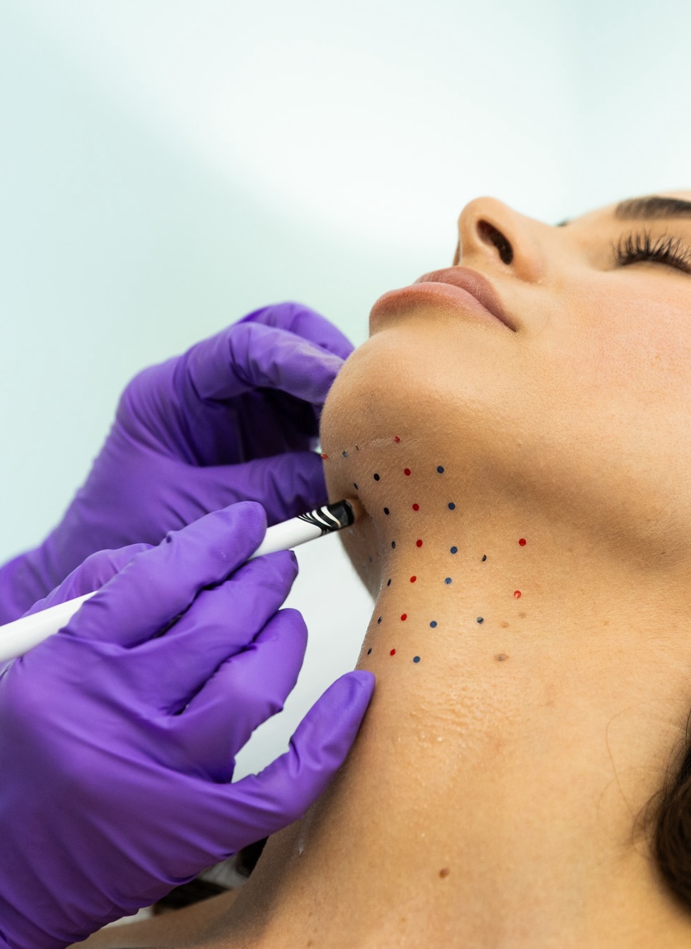 Professional marks patient's neck with dots.