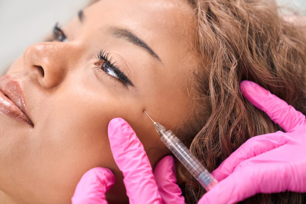Close up of young woman receiving Botox on side of face.