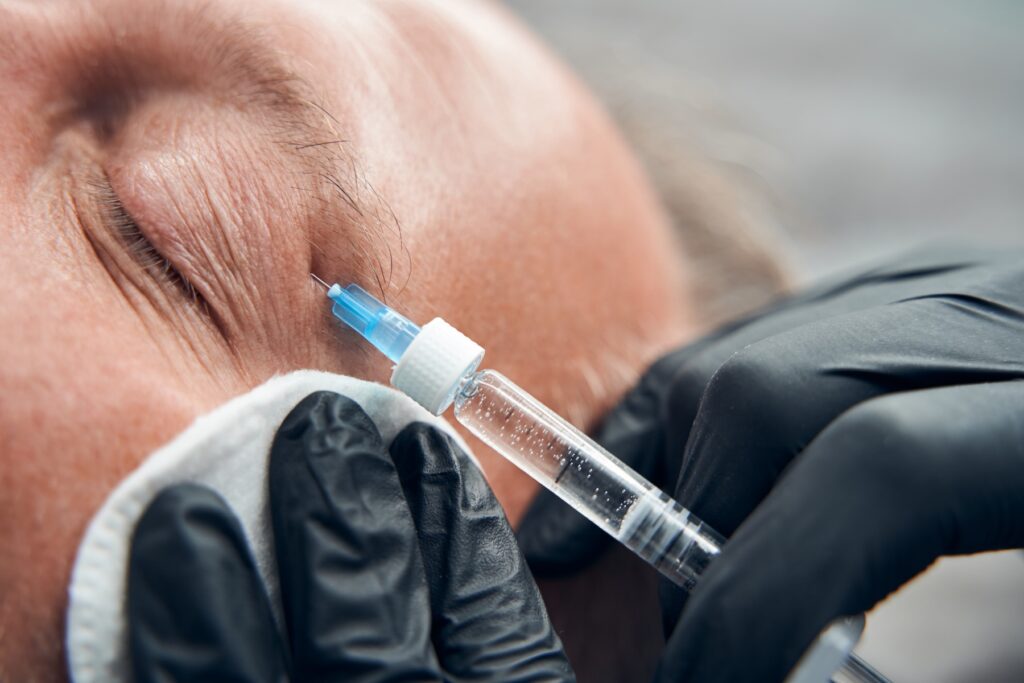 Close up doctor wearing gloves injecting filler in man's face
