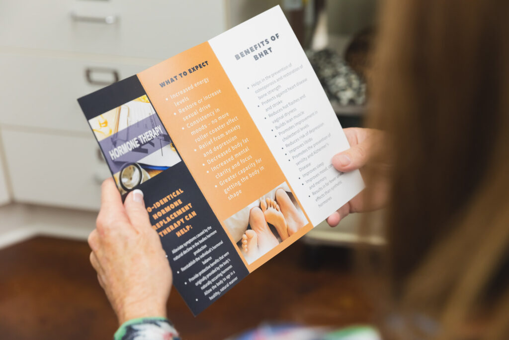 Woman looking at tri-fold of benefits from Hormone Therapy Replacement