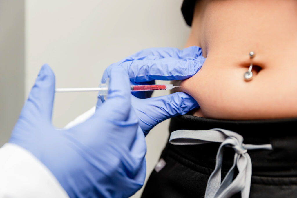 Patient receiving semaglutide injection in abdomen by doctor with blue gloves.