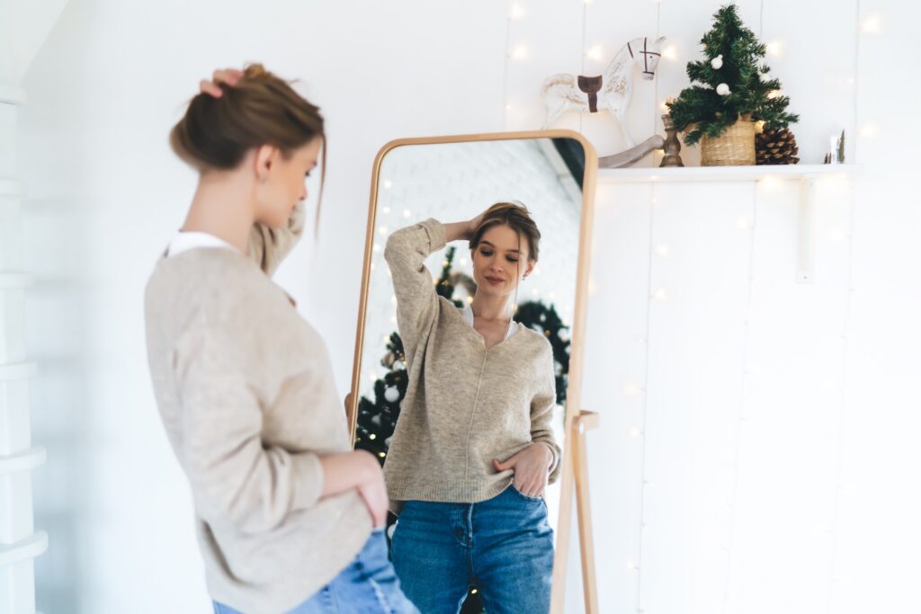 A woman examines her stomach in the mirror after starting pregnancy-safe skin care in Denville.