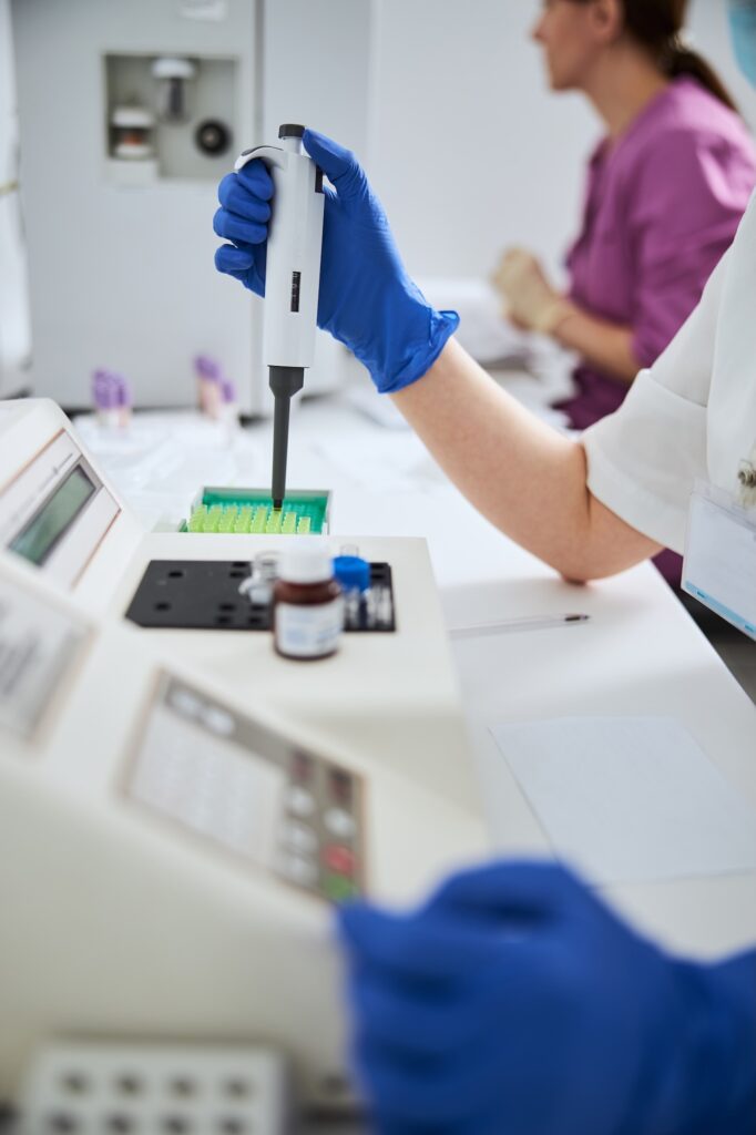 Cropped photo of a biochemist in latex gloves choosing a disposable plastic tip for an automated single-channel pipette