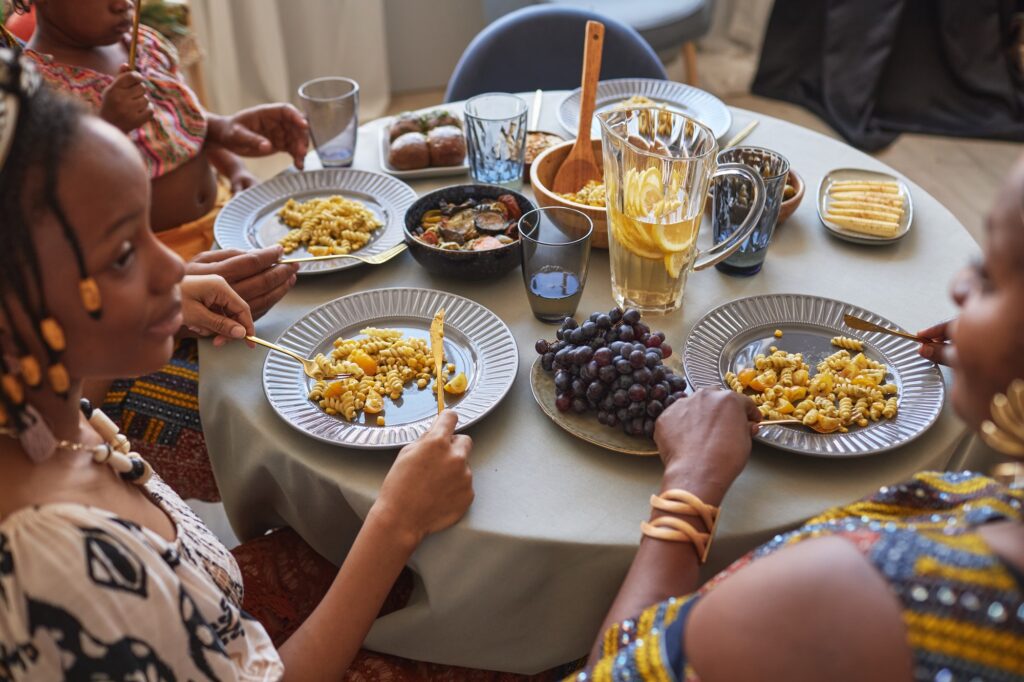 African family in traditional costumes having traditional dinner at table at home, the talking and celebrating holiday